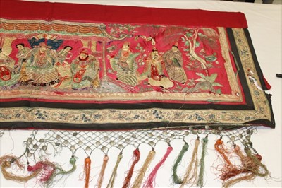 Lot 3056 - Chinese embroidered red silk banner.  Officials, deities and Gods in garden scene with pagoda and monkey holding a peach. Forbidden knot embroidered edging. Red cotton lining, knotted fringing with...