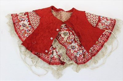 Lot 3078 - Chinese embroidered red silk child's cape with birds and flowers in forbidden stitch edging. Plus a length of hand embroidered edging with trees and birds and a dress length of embroidered red silk...