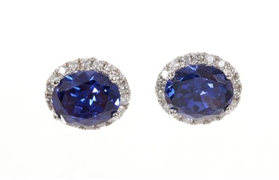 Lot 615 - Pair of Tanzanite and diamond cluster earrings, each with a large oval mixed cut Tanzanite , surrounded by a border of brilliant cut diamonds in white gold setting.