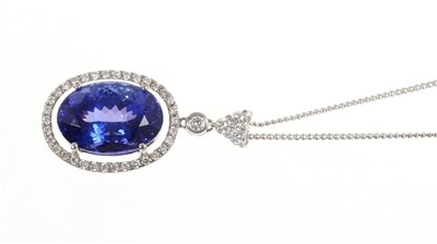 Lot 616 - Tanzanite and diamond pendant with an oval mixed cut tanzanite estimated to weigh approximately 6.5 carats surrounded by a border of brilliant cut diamonds, suspended from a diamond mount, in white...