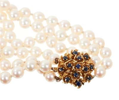 Lot 643 - Cultured pearl three-strand necklace with three strings of graduated cultured pearls measuring 6.0 to 9.3mm in diameter, on a sapphire and gold bombe clasp.