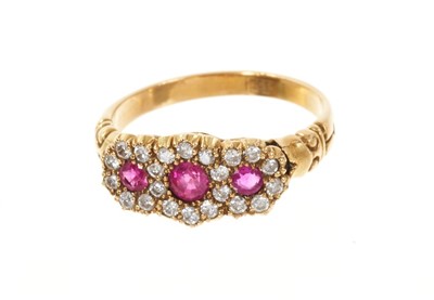 Lot 723 - Edwardian-style ruby and diamond triple cluster ring with three flower head clusters, each with a round mixed cut ruby surrounded by brilliant cut diamonds in claw setting with carved gold shoulder...