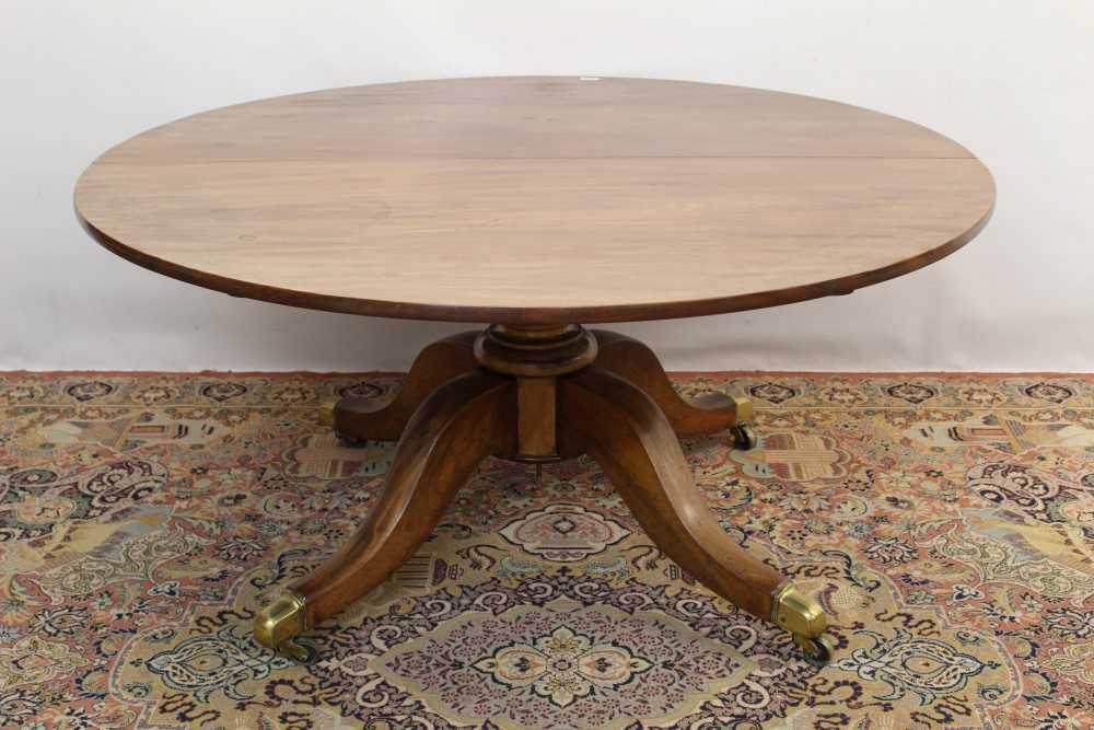 Lot 1689 - Substantial mahogany circular dining table, the expansive circular top on massive bulbous column and spread quadruped supports with brass cappings and castors, the base late Regency with later top,...