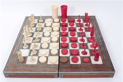 Lot 1296 - Collection of 19th century ivory and stained ivory chess and draughts pieces, the tallest 9cm and two dice shakers, housed within Anglo-Indian boxwood ivory and inlaid folding chess / backgammon bo...