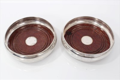 Lot 3410 - Pair of contemporary silver wine coasters with beaded edge and turned mahogany bases. Birmingham 1993. 14cm diameter