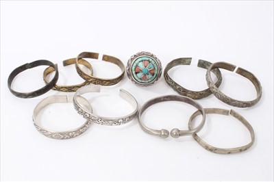 Lot 3496 - Group of Chinese and Eastern white metal and brass bangles, together with a large Thai/Eastern dress ring inset with coral and turquoise