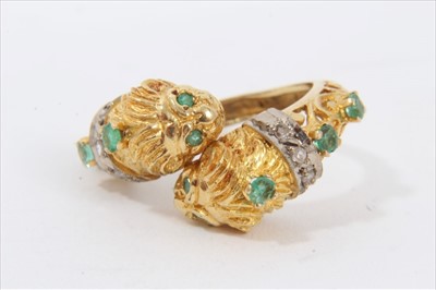 Lot 181 - Yellow metal lion's head cross over ring set with diamonds and emeralds