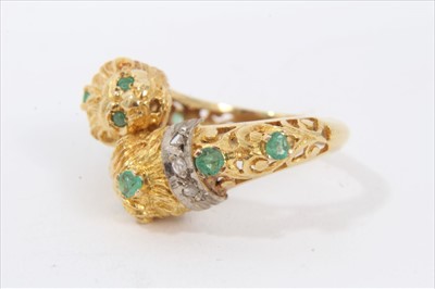 Lot 181 - Yellow metal lion's head cross over ring set with diamonds and emeralds