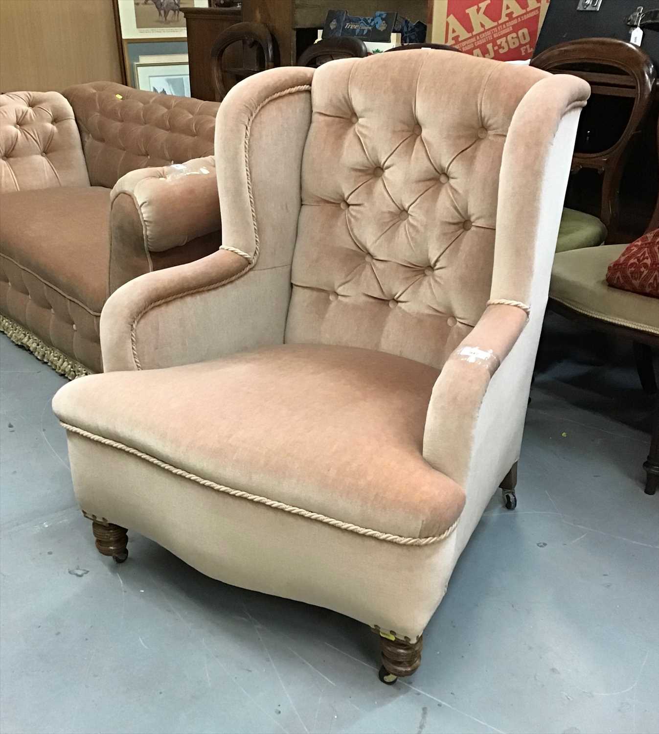Lot 947 - Victorian wing back chair upholstered in beige buttoned material on turned front legs