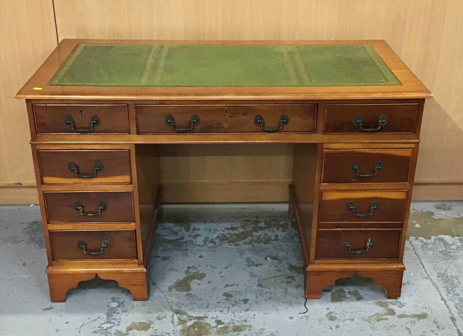 Lot 936 - Yew wood twin pedestal desk with tooled green leather top a arrangement of eight drawers below on bracket feet