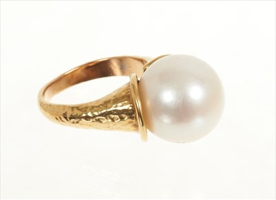 Lot 484 - Cultured pearl ring with a large single cultured pearl measuring approximately 12.8mm diameter in gold setting of organic modernist form with hammered finish. Signed 'Bagge', probably Eric Bagge (1...