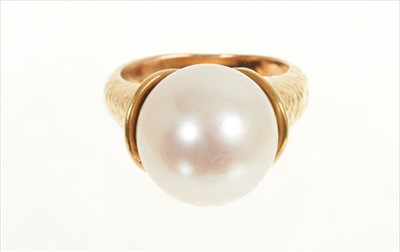 Lot 484 - Cultured pearl ring with a large single cultured pearl measuring approximately 12.8mm diameter in gold setting of organic modernist form with hammered finish. Signed 'Bagge', probably Eric Bagge (1...