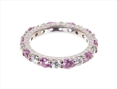 Lot 369 - Diamond and pink sapphire full band eternity ring in shared claw platinum setting
