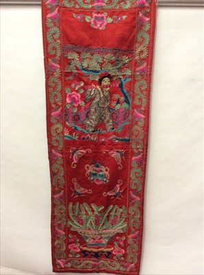 Lot 1653 - Chinese embroidered red silk vertical banner c1900s. Couch and satin stitch Girl playing wind instrument under a pine tree, scrolling foliage and flower border. Lined in blue cotton.