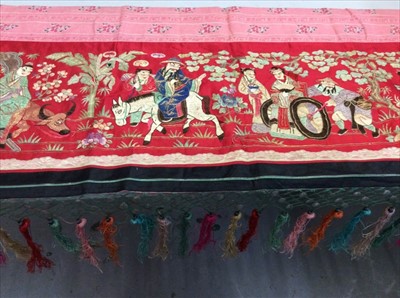 Lot 1655 - Chinese embroidered red silk panel c.19th century with couch and satin stitches, garden scene with figurers, animals, trees and flowers.  Woven silk borders with knotted fringe, metal disc beads an...