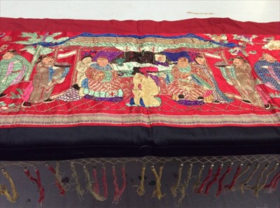 Lot 1657 - Chinese long embroidered red silk panel c1900s couch and satin stitch, figures with painted faces in garden scene with animals etc. Woven silk border, red cotton lining. Knotted fringe with meta...