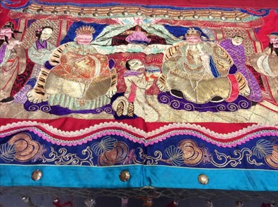 Lot 1658 - Chinese long embroidered red silk panel c1900s couch and satin stitch figures in garden scene with pagoda and horses etc. Red cotton lining with fringing, metal beads and tassels. Possibly a weddi...