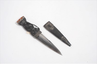 Lot 783 - 1930s Scottish Skean dhu dagger with silver mounts and orange glass set pommel, carved ebony hilt, tapered serrated blade, in sheath- hallmarked Edinburgh 1933, 17.2cm overall