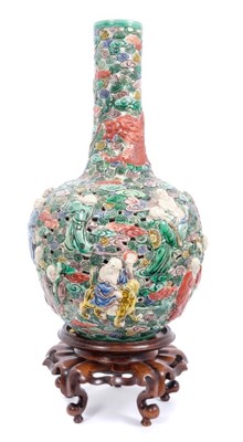 Lot 39 - Chinese famille verte reticulated bottle vase, decorated in relief with immortals and a dragon, six character seal mark to base, with a carved hardwood stand, vase measures 35cm height