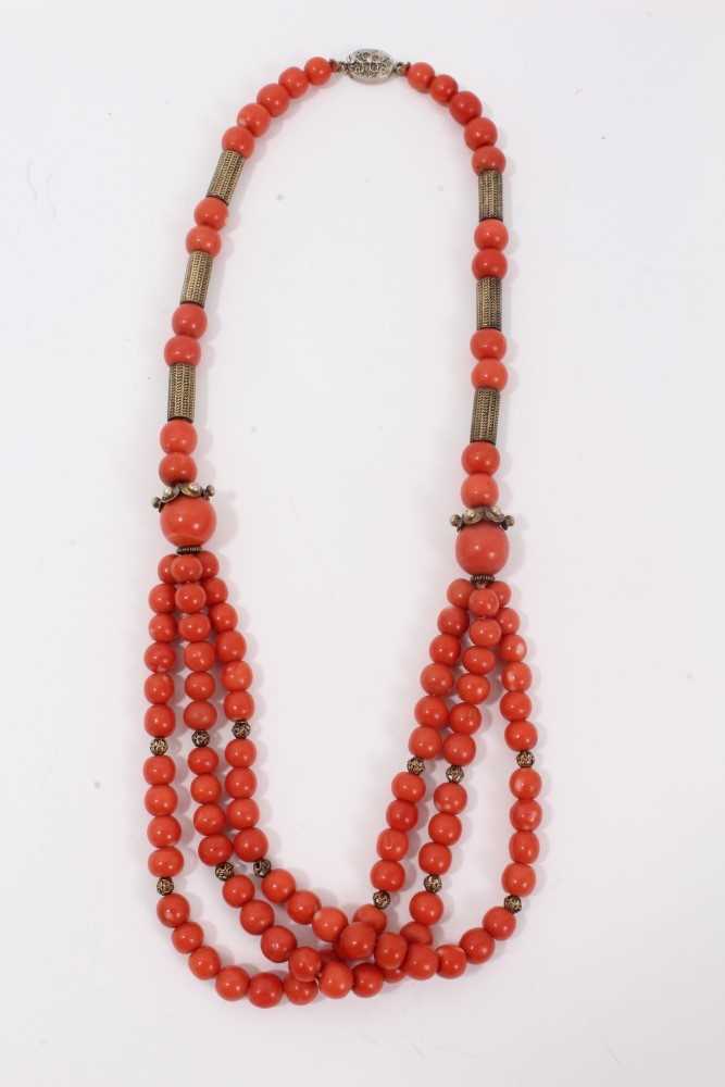 Lot 7 - Old Chinese coral necklace with spherical polished beads and metal spacers, terminating with three strands of beads and a silver clasp