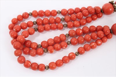Lot 7 - Old Chinese coral necklace with spherical polished beads and metal spacers, terminating with three strands of beads and a silver clasp