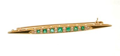 Lot 473 - Edwardian emerald and diamond bar brooch with seven graduated mixed cut emeralds interspaced by old cut diamonds in gold setting, in box