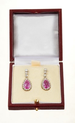 Lot 488 - Pair of diamond and pink sapphire pendant earrings, each with a pear cut pink sapphire surrounded by a border of brilliant cut diamonds suspended from three graduated brilliant cut diamonds, all in...