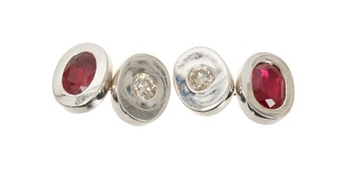 Lot 499 - Pair of diamond and ruby cufflinks, the oval white gold panels set with a brilliant cut diamond and the opposite side with an oval mixed cut ruby, in 18ct white gold setting.