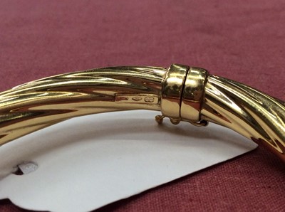 Lot 400 - 18ct gold hinged bangle with spiral reeded design
