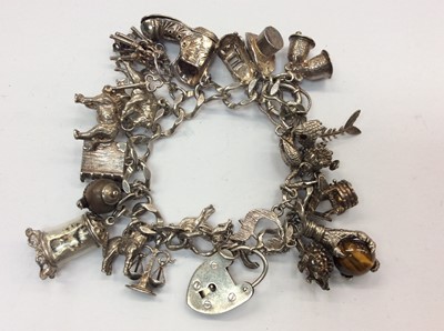 Lot 668 - Silver curb link charm bracelet with quantity of novelty charms