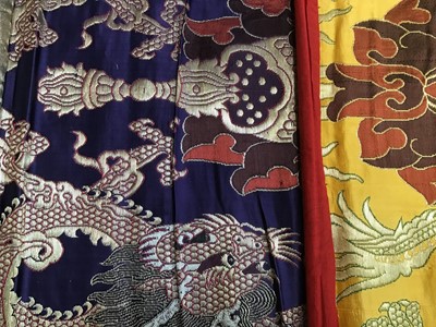 Lot 1780 - Chinese embroidered silk Dragon wall hanging plus three silk brocade dragon hangings.  Also two Tibetan Thanka   painted silk panels.