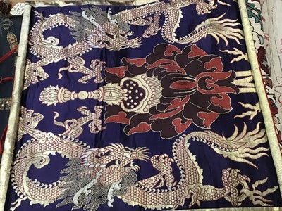 Lot 1780 - Chinese embroidered silk Dragon wall hanging plus three silk brocade dragon hangings.  Also two Tibetan Thanka   painted silk panels.