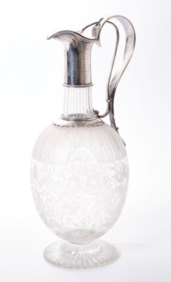 Lot 249 - Victorian cut glass claret jug of bulbous form, with etched floral decoration and star cut base, floral engraved silver plated collar, with integral handle and sprung hinged cover. 29.5cm overall h...