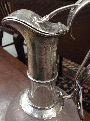 Lot 249 - Victorian cut glass claret jug of bulbous form, with etched floral decoration and star cut base, floral engraved silver plated collar, with integral handle and sprung hinged cover. 29.5cm overall h...