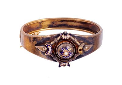 Lot 415 - Victorian Etruscan revival hinged bangle with seed pearl and blue enamel star and crescent moon motifs