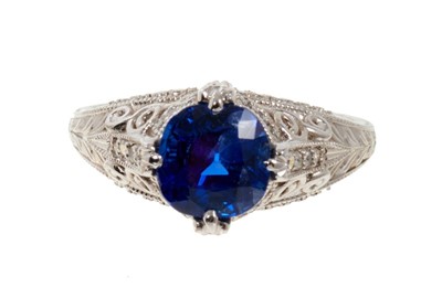 Lot 487 - A fine sapphire single stone ring with a natural cushion cut blue sapphire weighing 2.66ct in four claw setting with pavé set diamonds to the claws and bezel, pierced decoration on engraved shank....