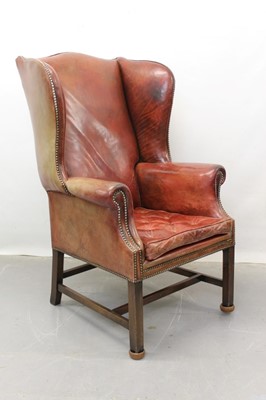 Lot 1301 - Georgian style red leather wing armchair with brass studded and buttoned decoration on square legs joined by stretchers