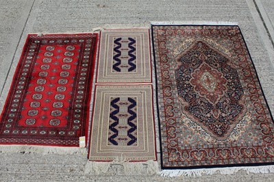 Lot 1398 - Pakistani rug with repeating medallion design on red ground, 155cm x 97cm, together with two other rugs