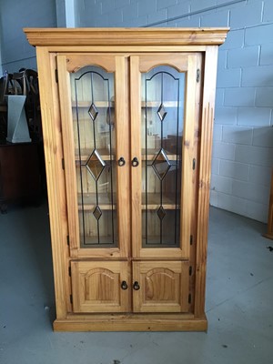 Lot 68 - Contemporary stained pine bookcase with two leaded glazed doors above enclosing three fixed shelves and two panelled doors below H180cm W104cm D37cm