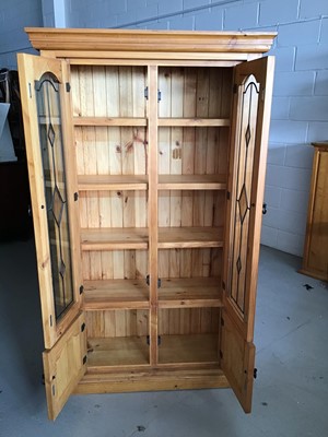 Lot 22 - Contemporary stained pine bookcase with two leaded glazed doors above enclosing three fixed shelves and two panelled doors below H180cm W104cm D37cm