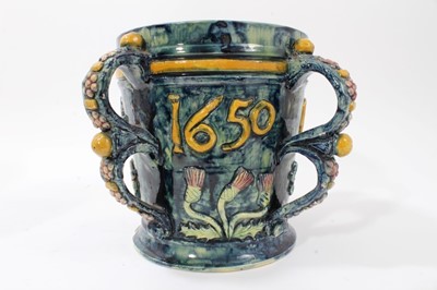 Lot 973 - Castle Hedingham Edward Bingham blue glazed pottery four handled jug / loving cup with applied floral decoration and 1650, the base marked No 22, E.W Bingham, 19cm high