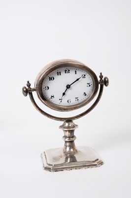 Lot 325 - George V silver gimble desk clock on square base with shaped corners, knopped stem and oval clock with white enamel dial (Birmingham 1926), Maker S.M. Levi Ltd, 13cm in height