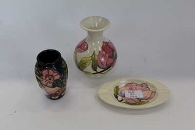 Lot 841 - Moorcroft pottery vase decorated with a pink flower on cream ground, similar ashtray and one other Moorcroft vase (3)