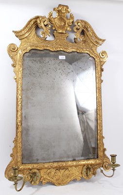 Lot 1320 - Early 18th century carved giltwood girandole mirror, original shallow bevelled plate and twin scrolling brass candle arms. 102 x 56cm