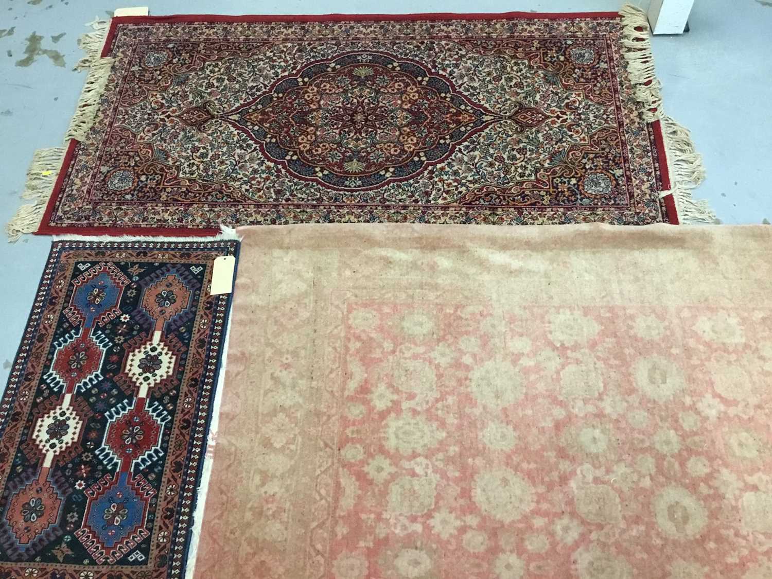 Lot 882 - Three rugs to include a Keshan rug with central medallion on red ground 180cm x 91cm, Persian rug 94cm x 55cm and a rug on pale red ground 205cm x 122cm