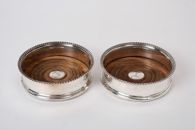 Lot 238 - Pair George III silver coasters with gadrooned borders and engraved armorials with wooden bases mounted with inset silver discs to centres  (London 1814), 13.5cm in diameter