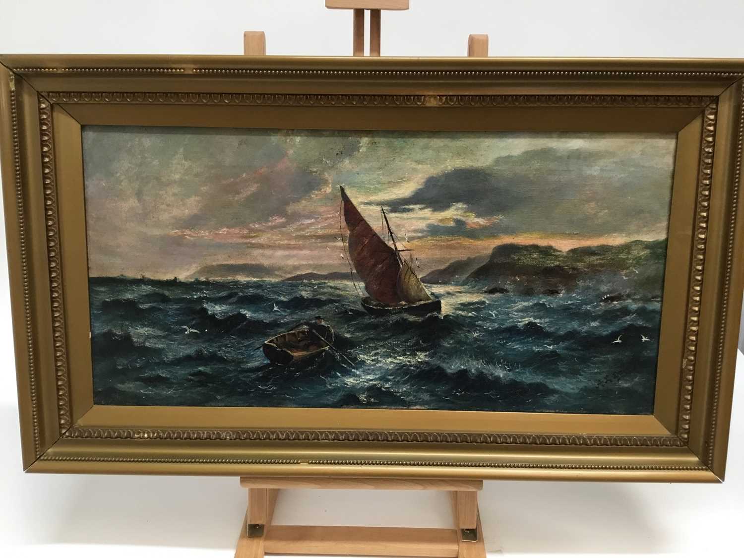 Lot 77 - A.L. Dogley, late 19th century, oil on canvas, Coastal scene with a dinghy and yacht off rocks, signed, in gilt frame, 30cm x 60cm