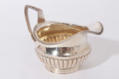 Lot 342 - George III silver cream jug of half-fluted potbellied form, with engraved crest, 5.8ozs