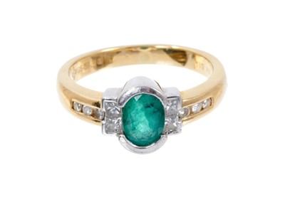 Lot 485 - Emerald and diamond ring with an oval mixed-cut emerald flanked by four princess cut diamonds and six channel set brilliant cut diamonds to the shoulders on 18ct yellow gold shank, millennium hallm...