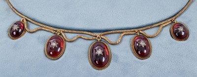 Lot 442 - Victorian gold and cabochon garnet fringe necklace with five graduated oval cabochon garnets with applied rose cut diamond stars, with rope twist borders and glazed locket compartment to the revers...